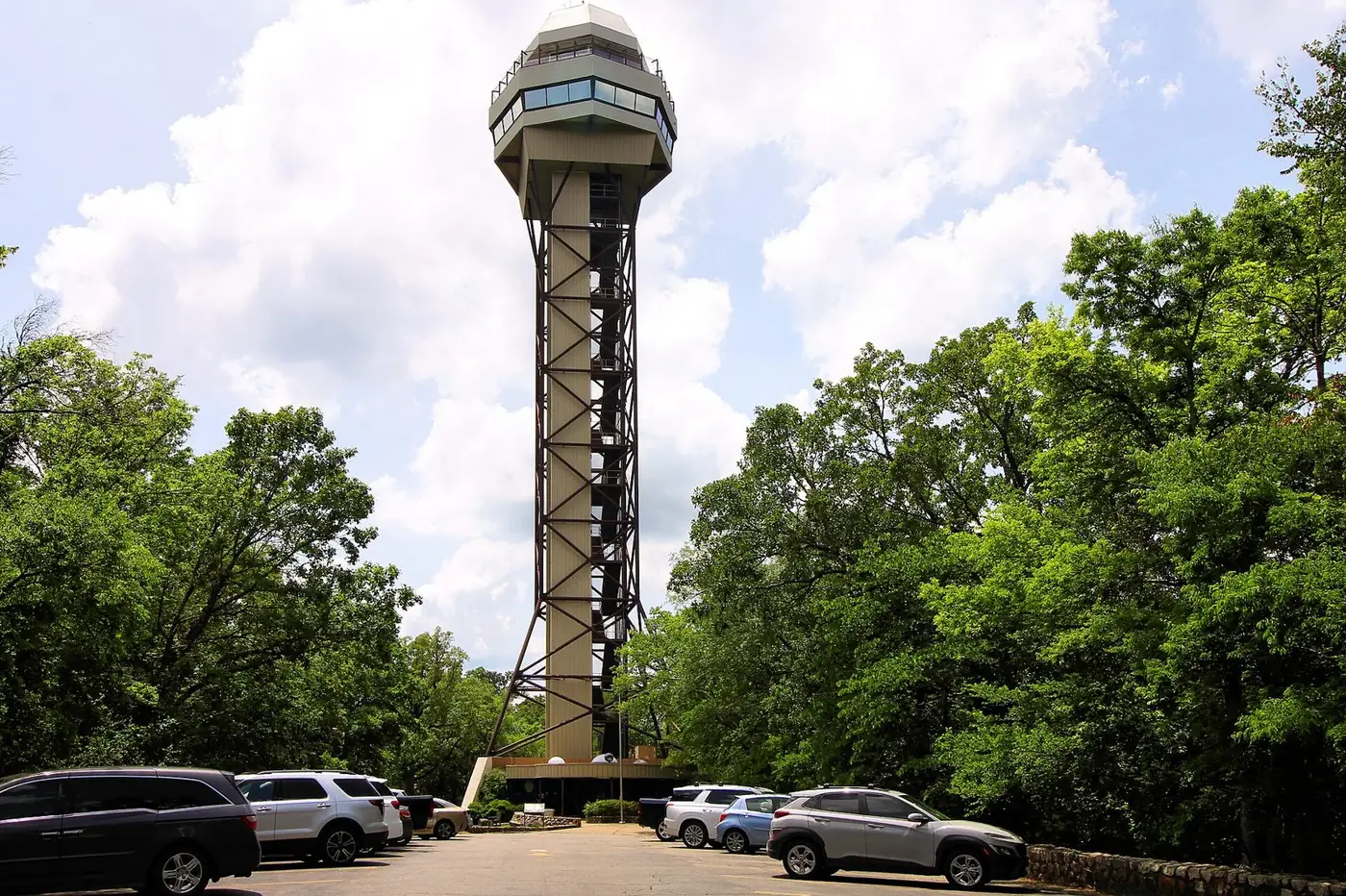 Hot Springs Mountain Tower rising above a wooded hilltop, with cars parked below